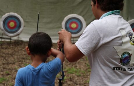 Thomas teaches archery to a boy